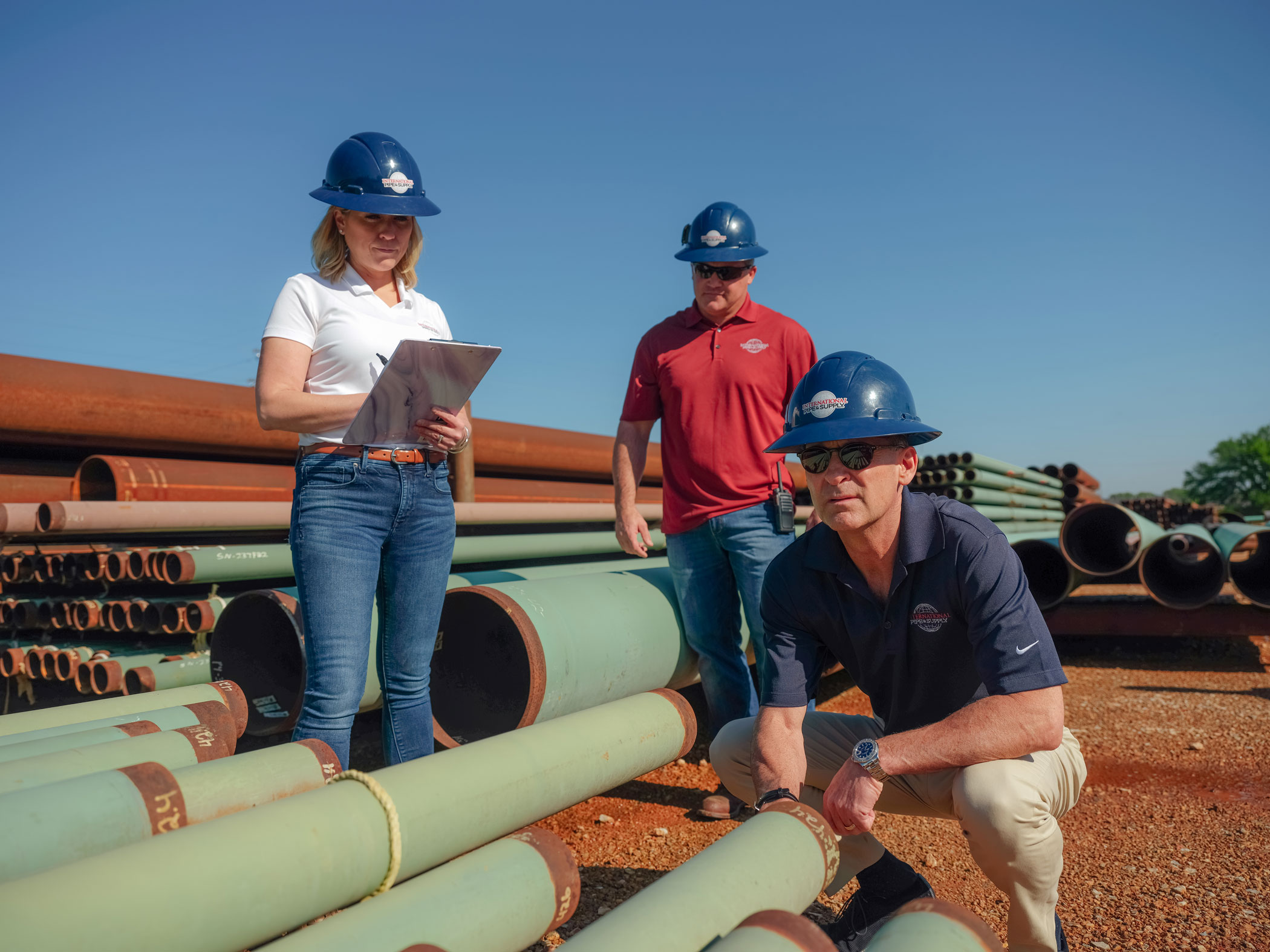 three people standing by large pipes